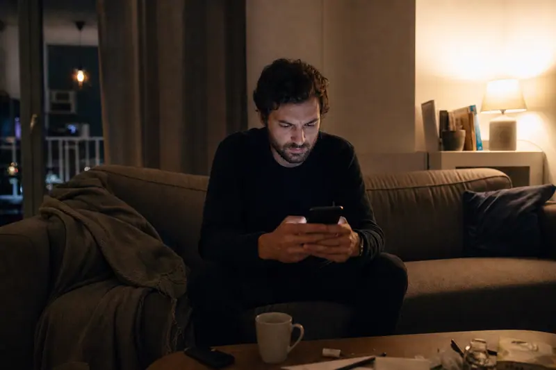 Homme vérifiant ses paiements récurrents sur son téléphone le soir