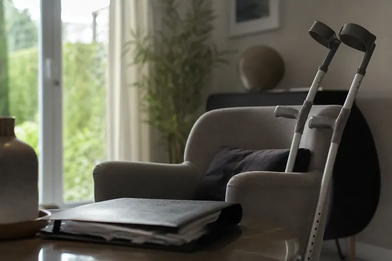 Béquilles appuyées contre un fauteuil près d'un dossier médical fermé