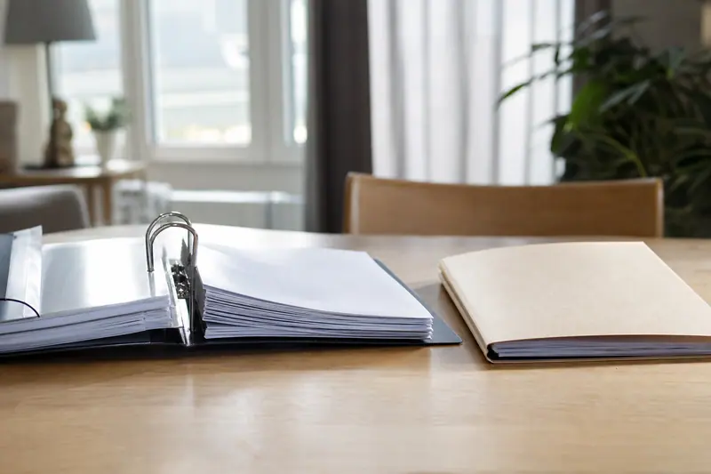 Classeur de documents financiers ouvert à côté d'une nouvelle chemise cartonnée
