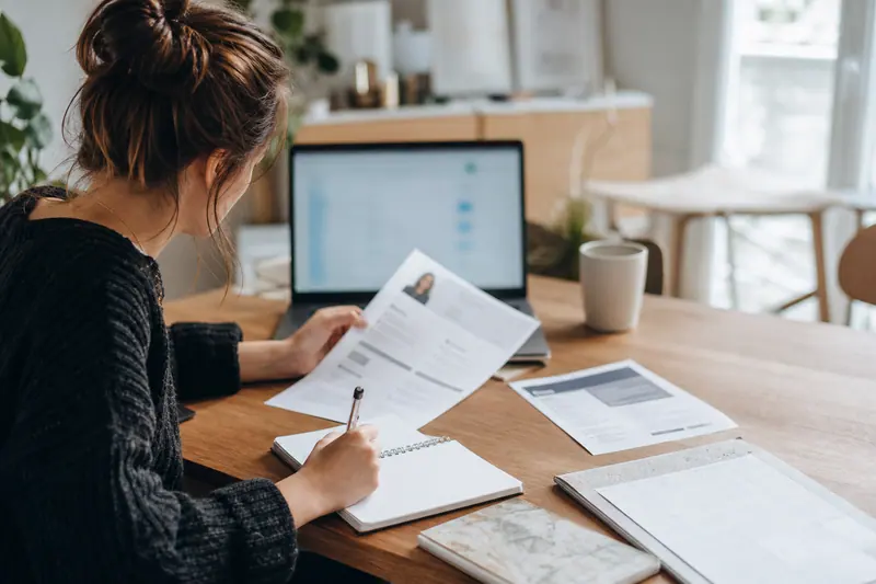 Candidate prépare son dossier d’alternance sur une table lumineuse avec ordinateur et documents.