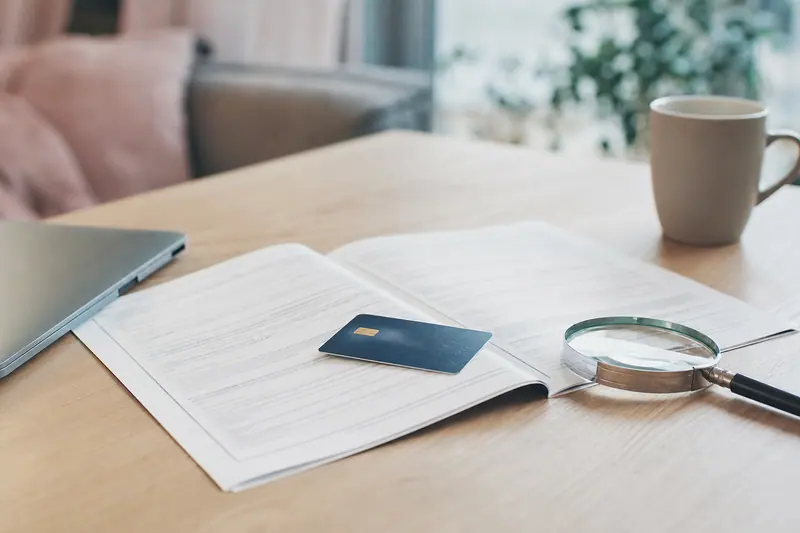 Carte bancaire posée sur un document avec une loupe