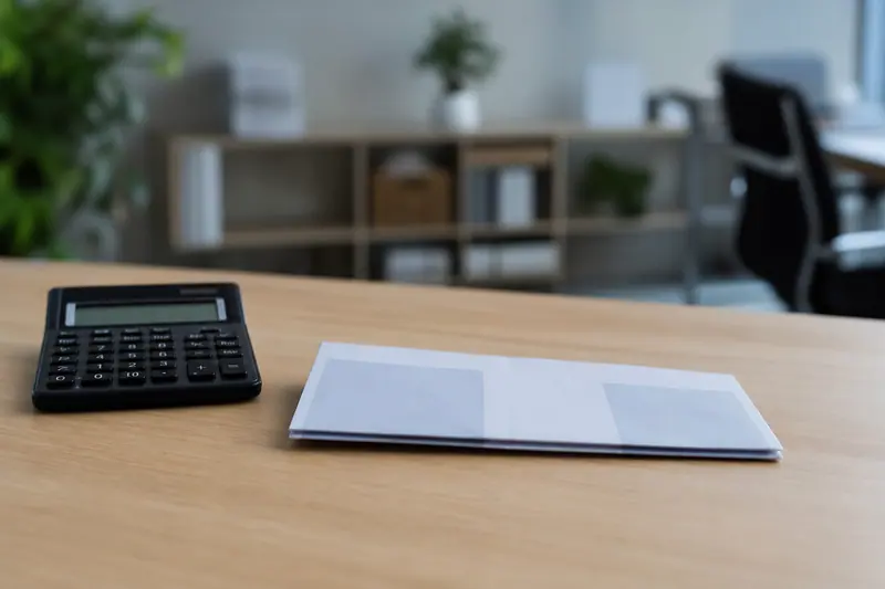 Calculatrice posée près d'un bulletin de paie fermé sur un bureau