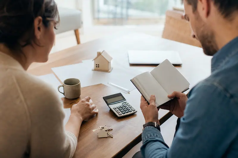 Documents immobiliers, clés et épargne posés sur une table de salon.