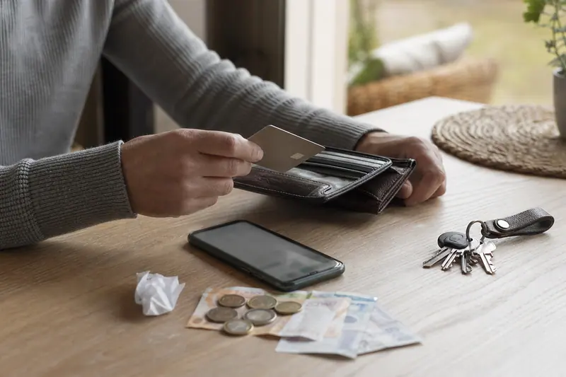 Carte de paiement, téléphone et espèces posés sur une table de cuisine.