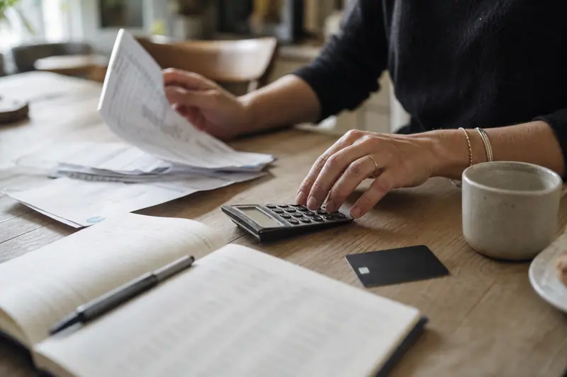 Mains classant relevés et calculatrice pour régulariser un compte bancaire négatif.