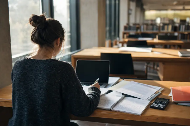 Étudiante préparant un dossier de candidature dans une bibliothèque universitaire lumineuse.