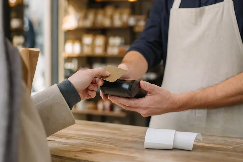 Commerçant utilisant un terminal de paiement au comptoir de sa boutique.