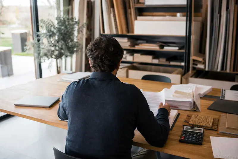 Dirigeant préparant des documents financiers dans un atelier-bureau lumineux.