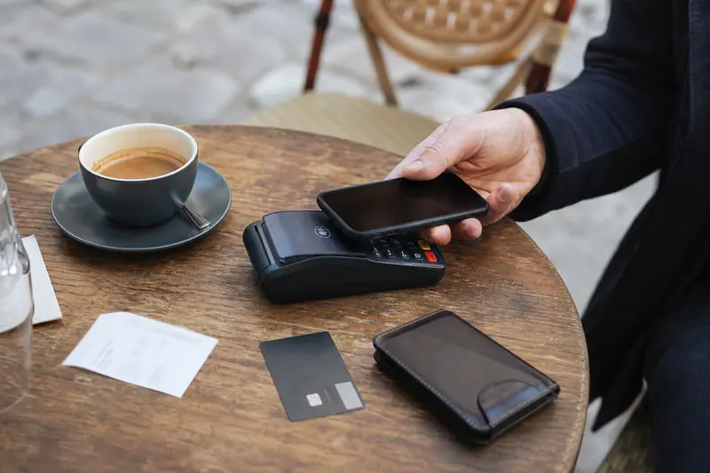 Paiement sans contact avec smartphone et carte sur une table de café.