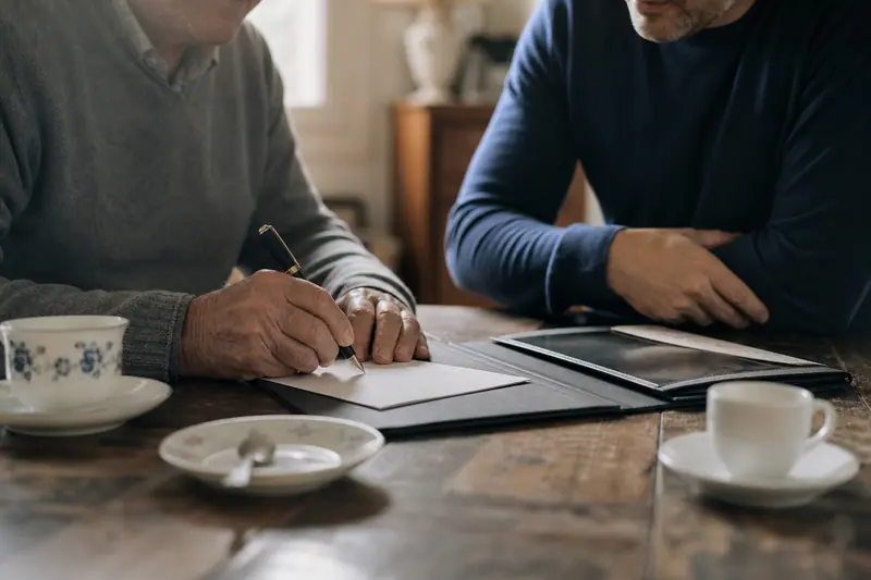 Parent et enfant adulte signant un document manuscrit à la table familiale