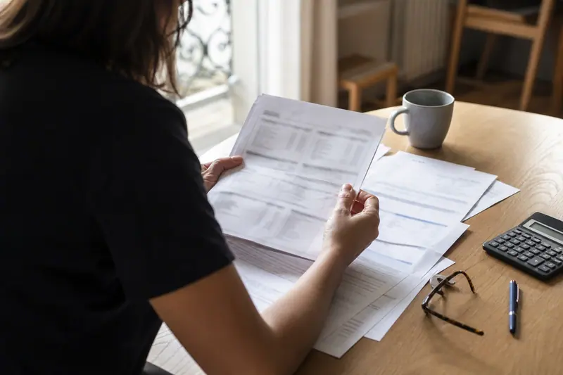 Personne consultant des documents financiers imprimés sur une table lumineuse.